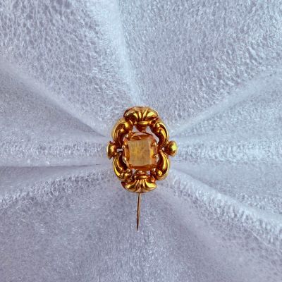 une broche dorée posée sur un tissu blanc