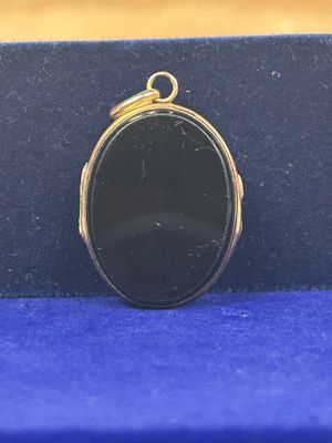 un pendentif ovale en pierre noire posé sur un tissu bleu