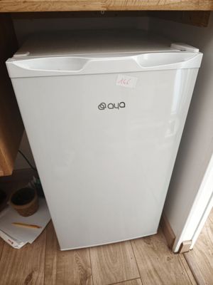 un petit réfrigérateur blanc dans le coin d'une pièce