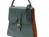 the green and brown handbag is sitting on a white surface
