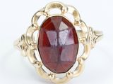 a close up of a gold ring with a red stone in it