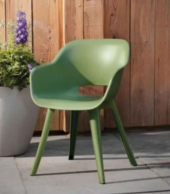 une chaise verte posée à côté d'une plante en pot sur une terrasse