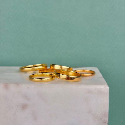 three gold wedding rings on a marble block against a green background