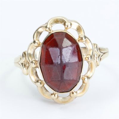 a close up of a gold ring with a red stone in it