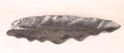 a silver leaf shaped object on a white surface