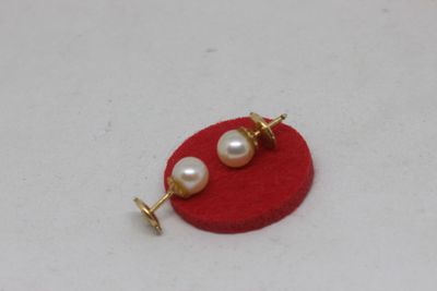 a close up of a pair of pearl earrings on a red surface
