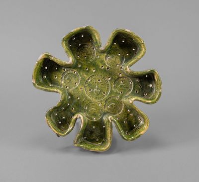 a close up of a green flower shaped object on a gray surface