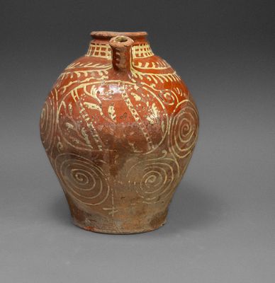 a brown vase with designs on it on a gray surface