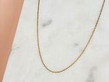 un collier à chaîne en or posé sur une surface en marbre