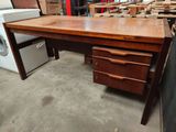 a wooden desk with drawers and a washing machine in the background