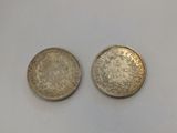 two silver coins sitting next to each other on a white surface