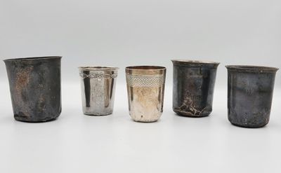 un ensemble composé de quatre coupes en argent et d'une coupe en argent posées sur une surface blanche