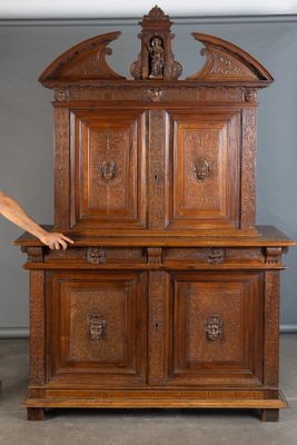 un homme debout à côté d'une grande armoire en bois