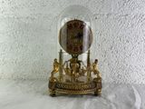 a clock that is under a glass dome on a table