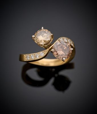un gros plan d'une bague en or sertie de deux diamants sur un fond noir