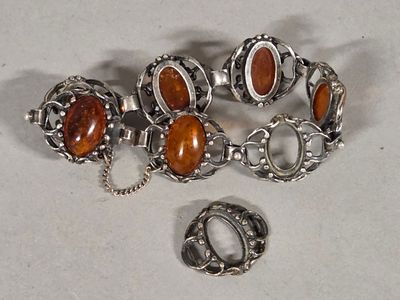 two pieces of silver and amber jewelry on a white surface