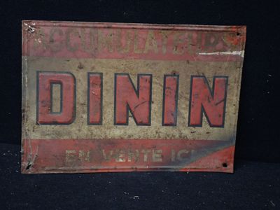 une vieille enseigne en tôle portant l'inscription « dinin », posée sur une surface noire