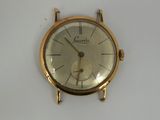 a gold watch on a white surface with a white background