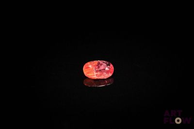 un diamant rouge sur une surface noire, dans l'obscurité