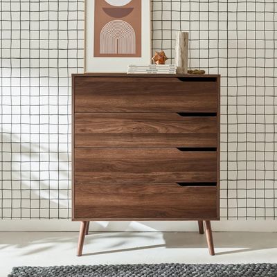 un gros plan d'une commode placée devant un mur sur lequel est accroché un tableau