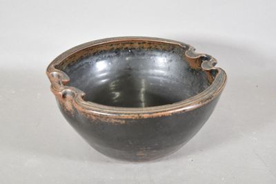 un bol noir et marron posé sur une surface blanche