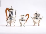 trois théières en argent et une cafetière posées sur une table