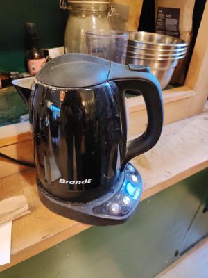 une cafetière noire posée sur une étagère en bois