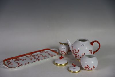 un service à thé blanc et rouge posé sur une table blanche