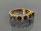 an image of a gold ring with blue sapphires and diamonds