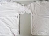 two white t - shirts sitting on top of a table next to each other