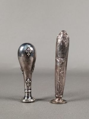 deux cuillères en argent et un repose-cuillère posés sur une surface grise