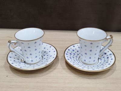 deux tasses et soucoupes sont posées sur une table en bois