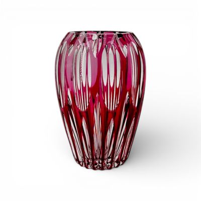 un vase rouge posé sur une surface blanche