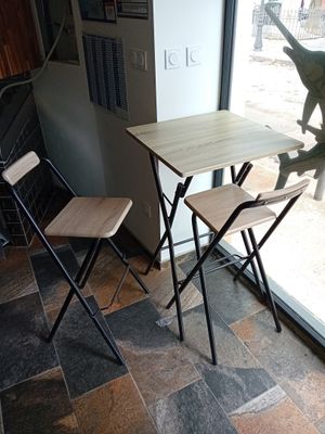 une petite table et deux chaises devant une fenêtre