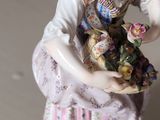 a figurine of a woman holding a basket of flowers