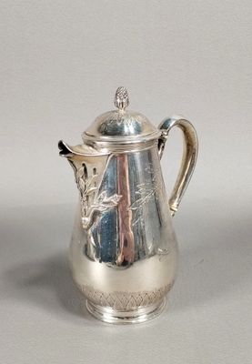 une cafetière en argent avec un couvercle, posée sur une table
