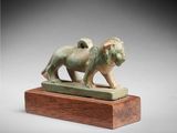 a bronze statue of a lion on a wooden base