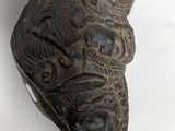 a close up of a carved mask on a white surface
