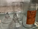 a glass shelf that has a lot of glass jars on it