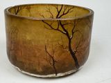 a brown and black bowl with trees painted on it