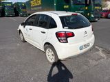 a white car parked in a parking lot with a green truck in the background