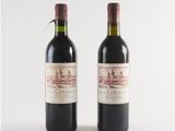 two bottles of red wine sitting next to each other on a white surface