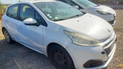 La petite voiture blanche est garée sur un parking, à côté d'autres voitures.