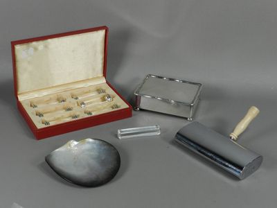 une boîte contenant des objets en argent posée sur une table, à côté d'un couteau et d'autres objets