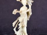 une figurine chinoise en ivoire sculpté représentant une femme tenant des fleurs