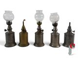 three old fashioned oil lamps are lined up on a white surface