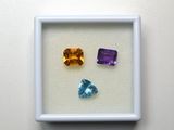 trois pierres précieuses de couleurs différentes, encadrées de blanc, sur un fond blanc