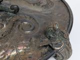 a silver plate with a bird on it on a white surface
