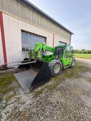 a green tractor parked in front of a building next to a building