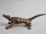 brass figurine of a lizard on a white background
